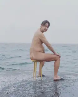 A person sitting on a three legged stool called Klaus in Copenhagen 2018.